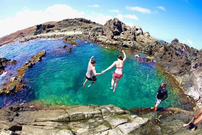 Visitors swimming in the Natural Pool as waves break behind the rocks