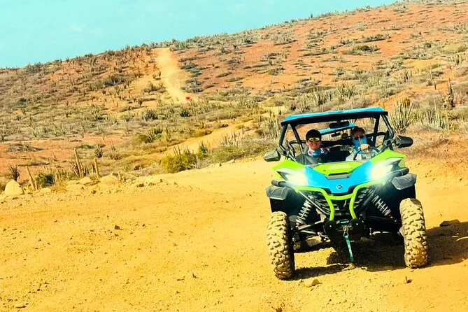 Orange multi-seat UTVs parked on a dirt road